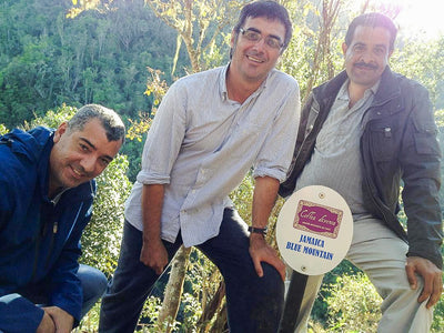 Owner of Coffea Diversa estate smiling with farm workers next to a Jamaica Blue Mountain sign