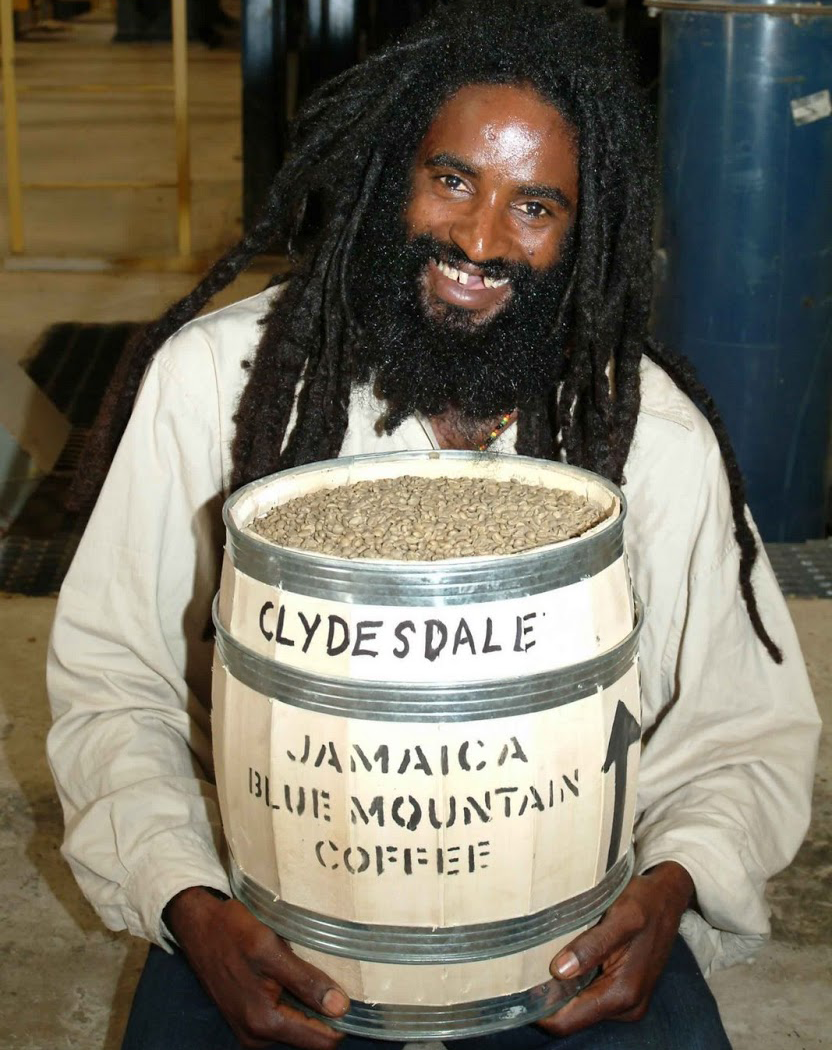 Man smiling while holding a barrel full of Jamaica Blue Mountain coffee beans