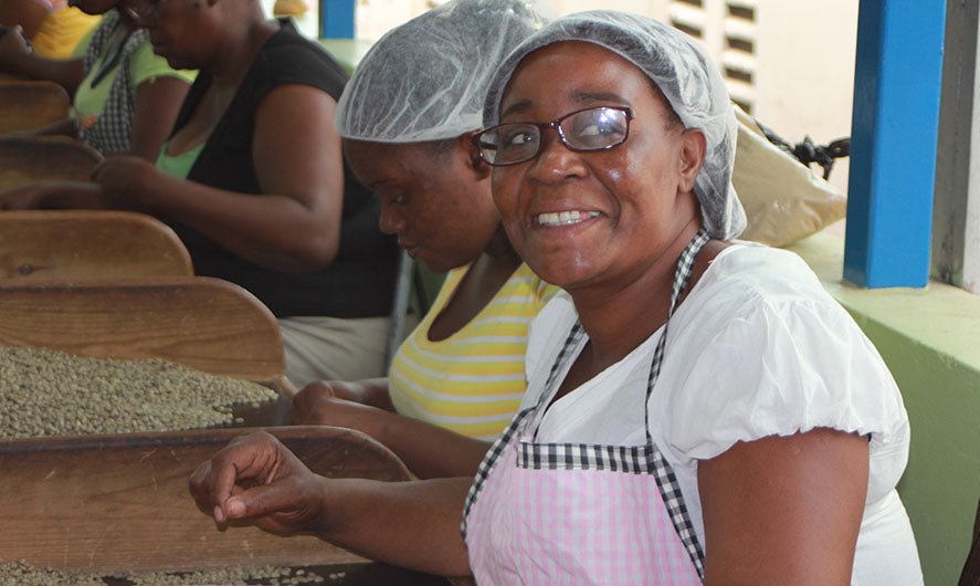 Farm worker in Jamaica smiling while sorting coffee beans