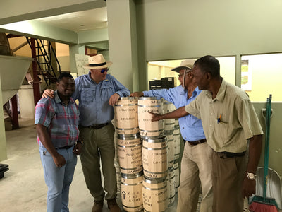 Farm workers standing next to Jamaica Blue Mountain coffee barrels from Stoneleigh estate