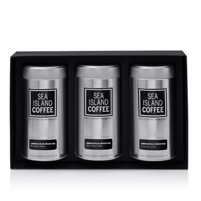 Three Sea Island Coffee tins in a black box on a white background