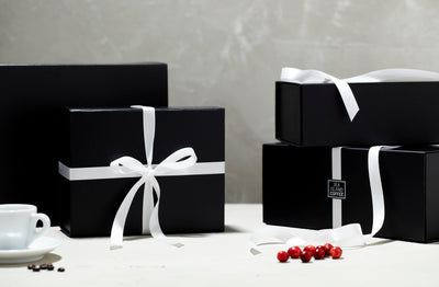Gift boxes with white ribbon from Sea Island Coffee sitting next to a coffee cup and some berries