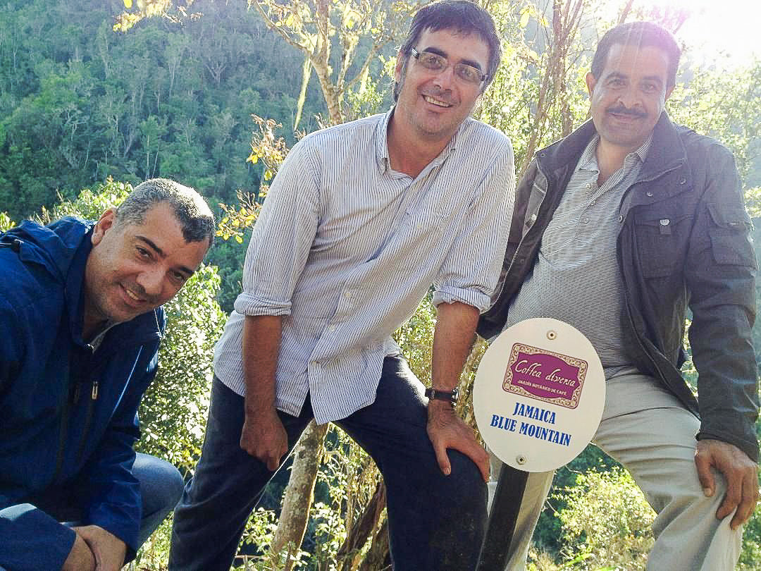 Coffea Diversa estate owner standing with coffee farmers next to a Jamaica Blue Mountain sign
