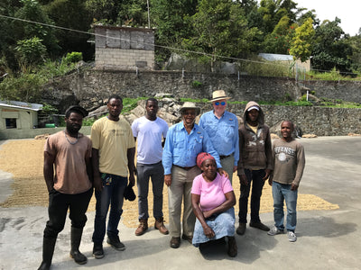 Farm workers and Stoneleigh estate owner standing next to Jamaica Blue Mountain coffee beans being laid out to dry in the sun